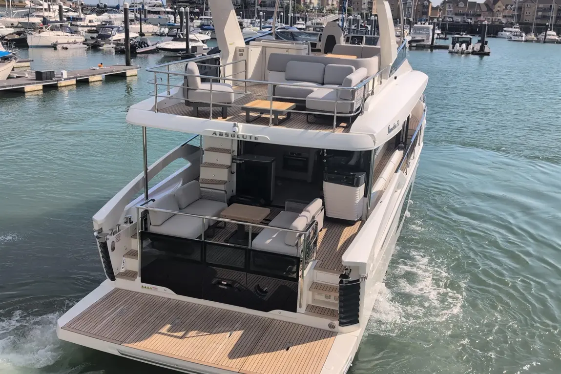Luxury Absolute yacht cruising in marina, featuring spacious decks, comfortable seating, and clear blue water.